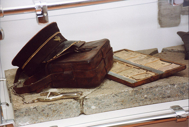 Zdjęcie przedstawia eksponaty muzeum - czapkę kolejarską, torbę i kasownik biletów.