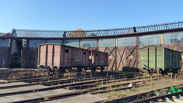 Zdjęcie przedstawia hale wachlarzową i stojące przed nią drewniane wagony.